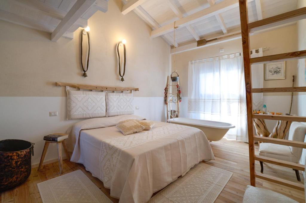 Is Perdas Rural Retreat & Spa في Gergei: غرفة نوم مع سرير وحوض استحمام
