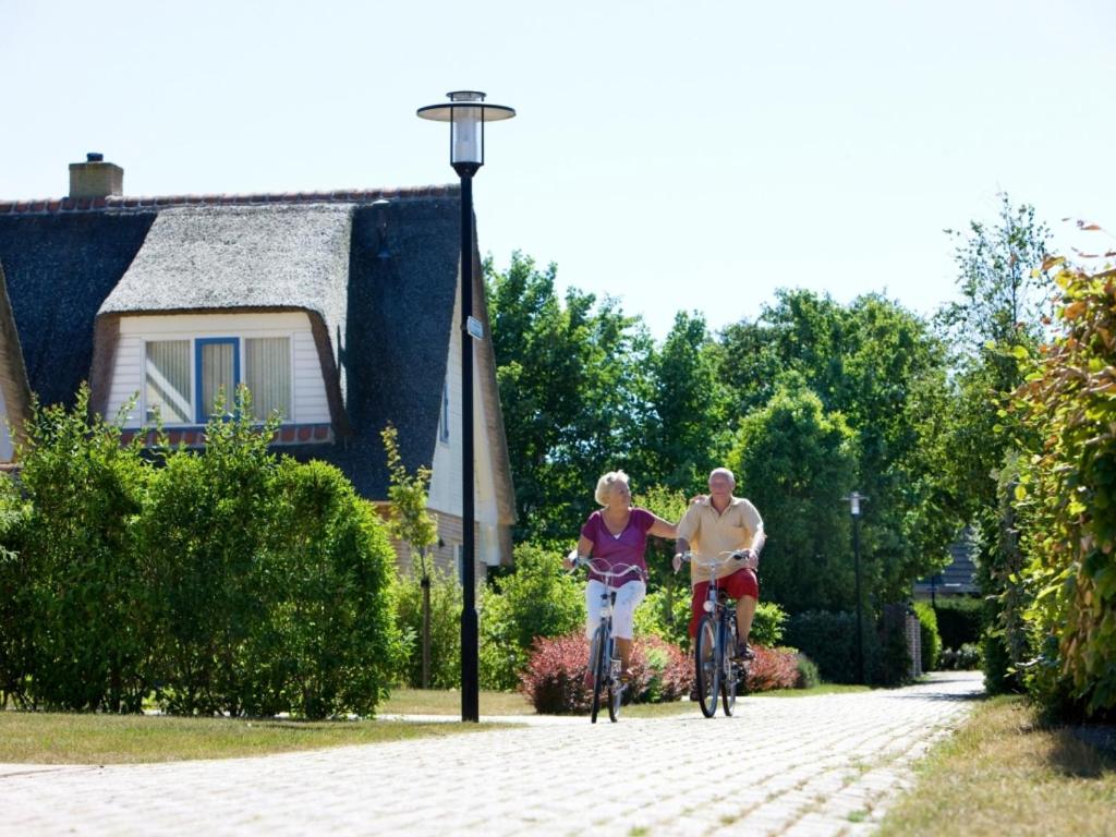 a man and woman riding bikes down a street at Landal Villapark Vogelmient in De Koog