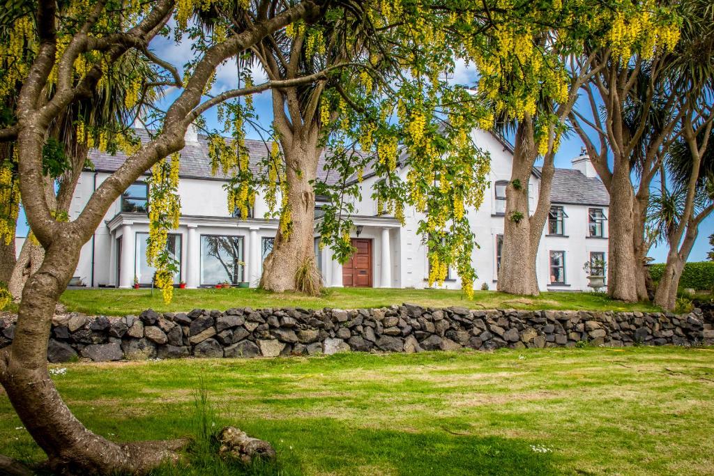 une maison blanche avec un mur en pierre et des arbres dans l'établissement Altahammond House, à Carrickfergus