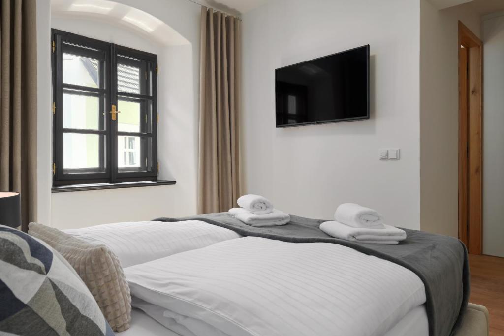 two beds in a room with a tv on the wall at Pension Kristian by KH in Český Krumlov