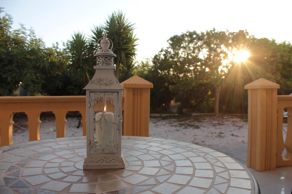 une lanterne assise sur une table avec le soleil en arrière-plan dans l'établissement La Lanterna delle Fate, à Otrante