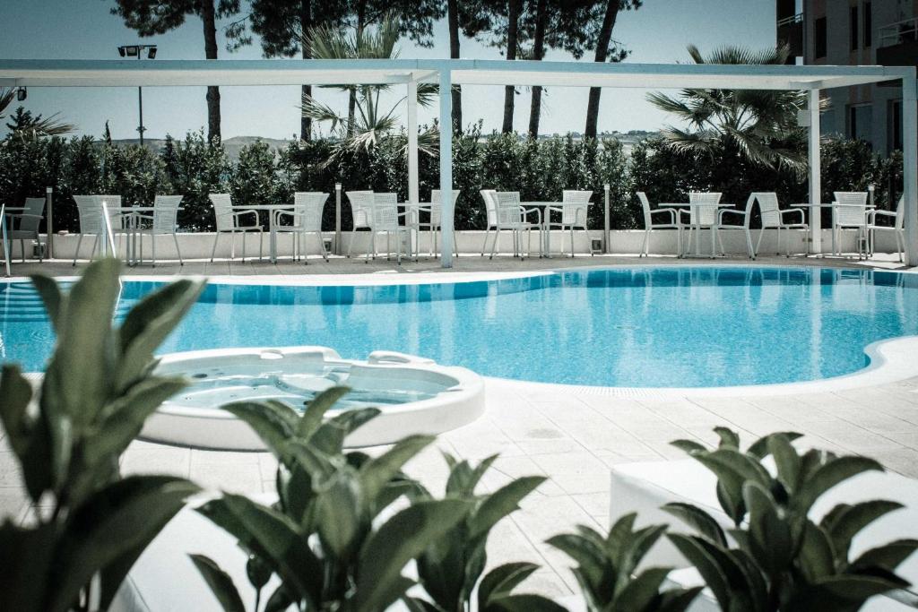 - une piscine avec des tables et des chaises blanches dans l'établissement Hotel Europa, à Termoli