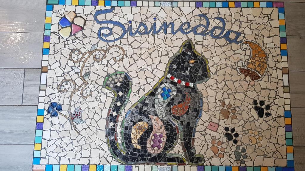 un mosaico di un gatto nero seduto su un tavolo di Sisinedda a Siniscola