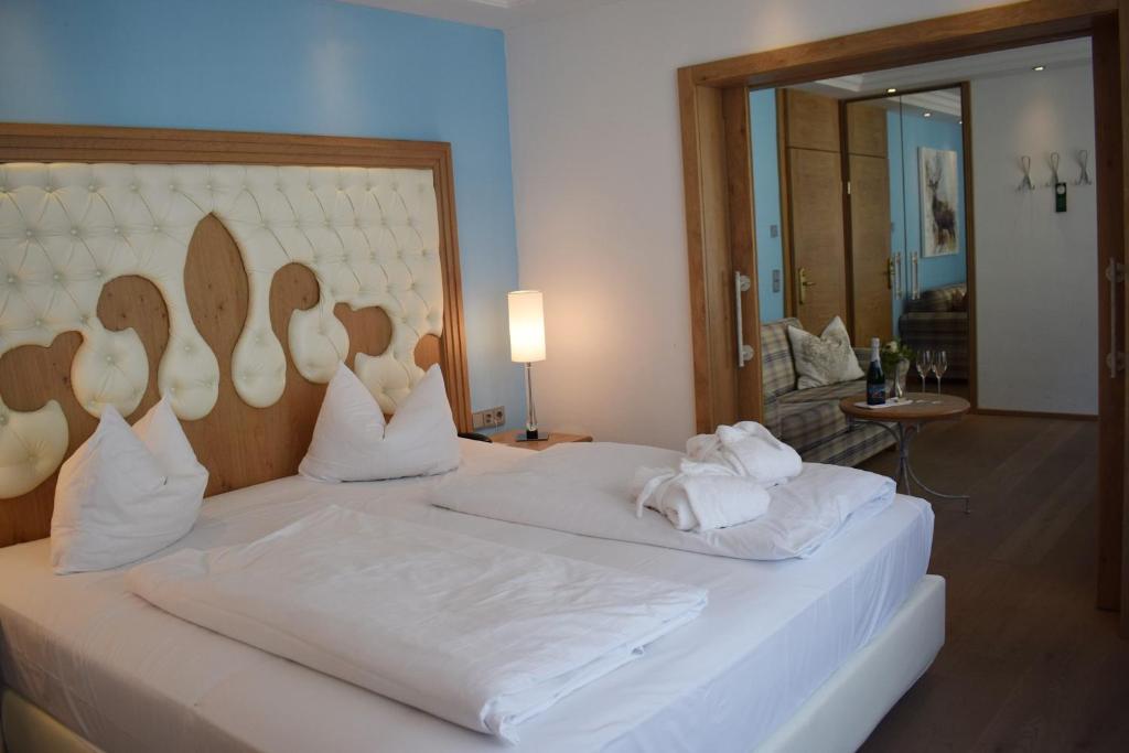 Wellness Hotel Bayerischer Hof في ريمباخ: غرفة نوم بسرير كبير عليها شراشف ووسائد بيضاء