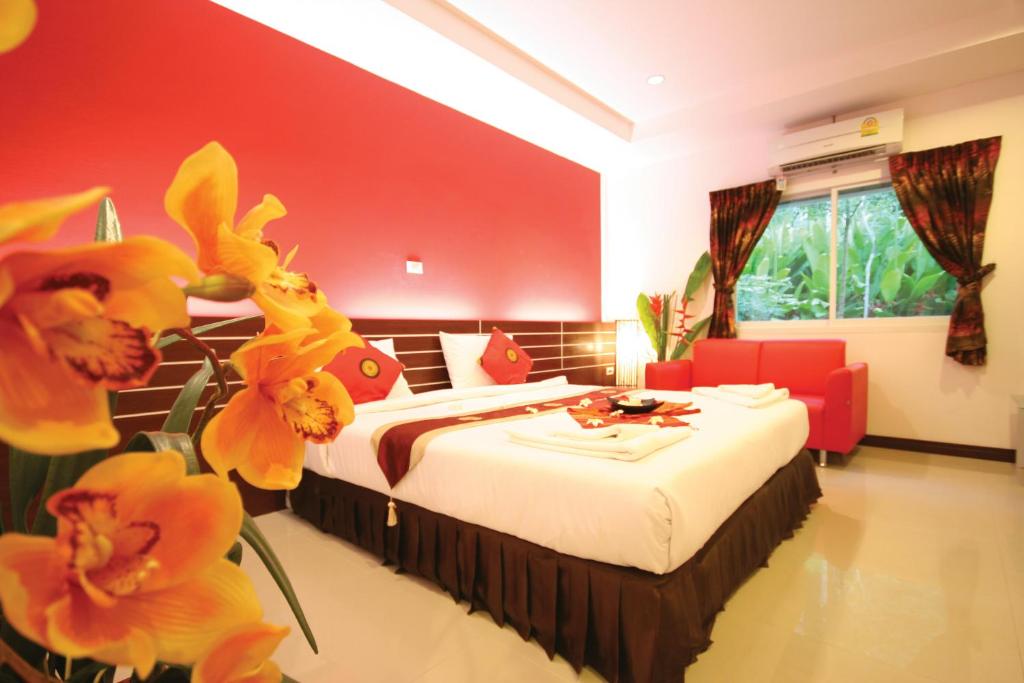 a bedroom with a bed with red walls and yellow flowers at Pantharee Resort in Krabi town