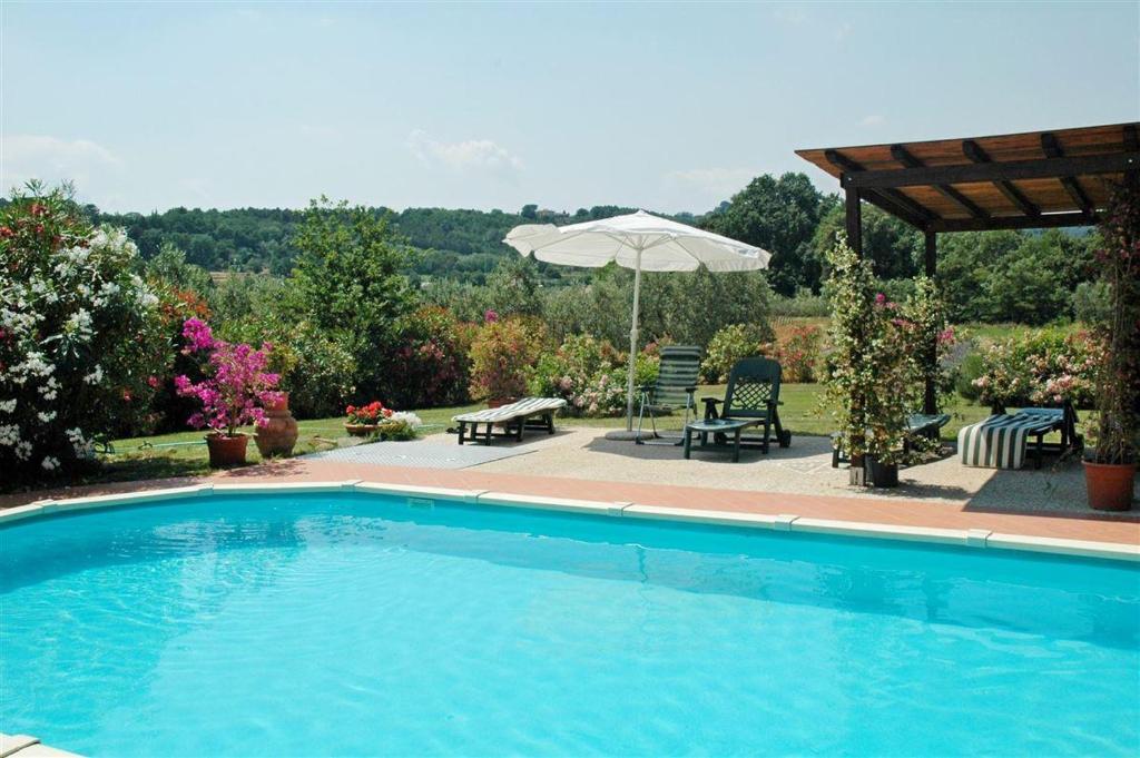 einen Pool mit einem Tisch, Stühlen und einem Sonnenschirm in der Unterkunft La Piaggia in Altopascio