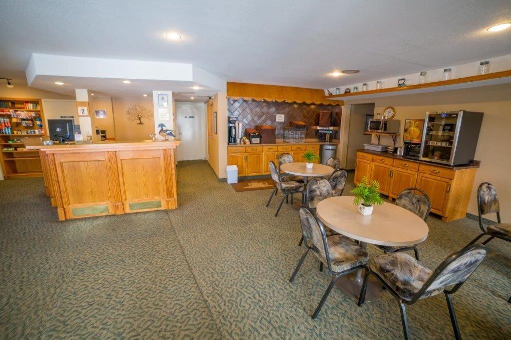 Habitación grande con 2 mesas y cocina. en Woodland Inn, en Meadow Lake