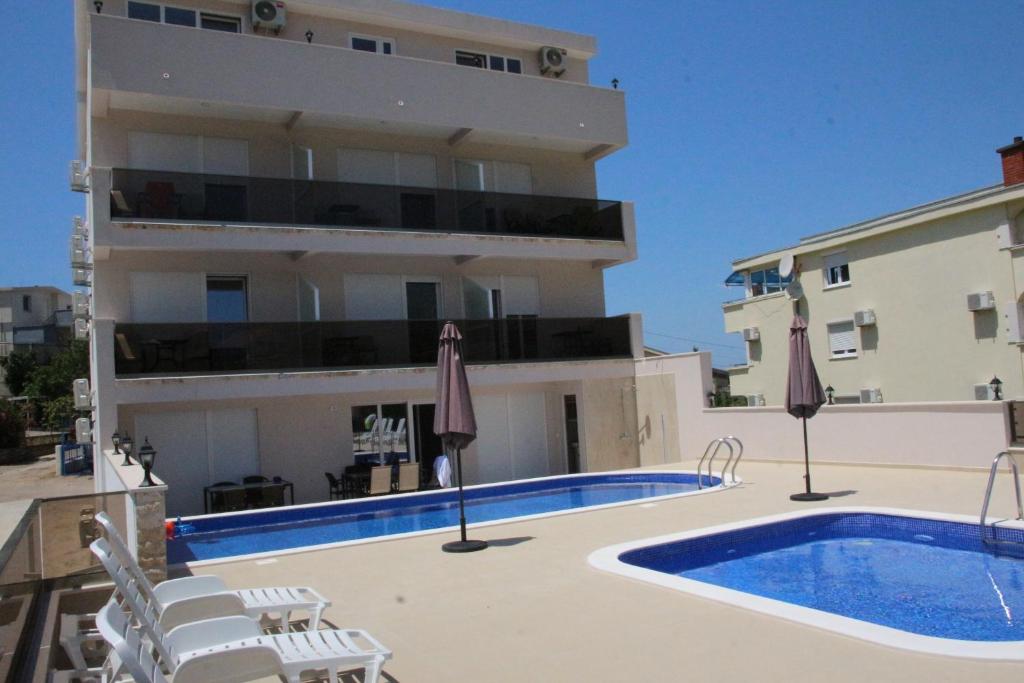 a large apartment with a swimming pool and a building at Zigovic Apartmani in Bar