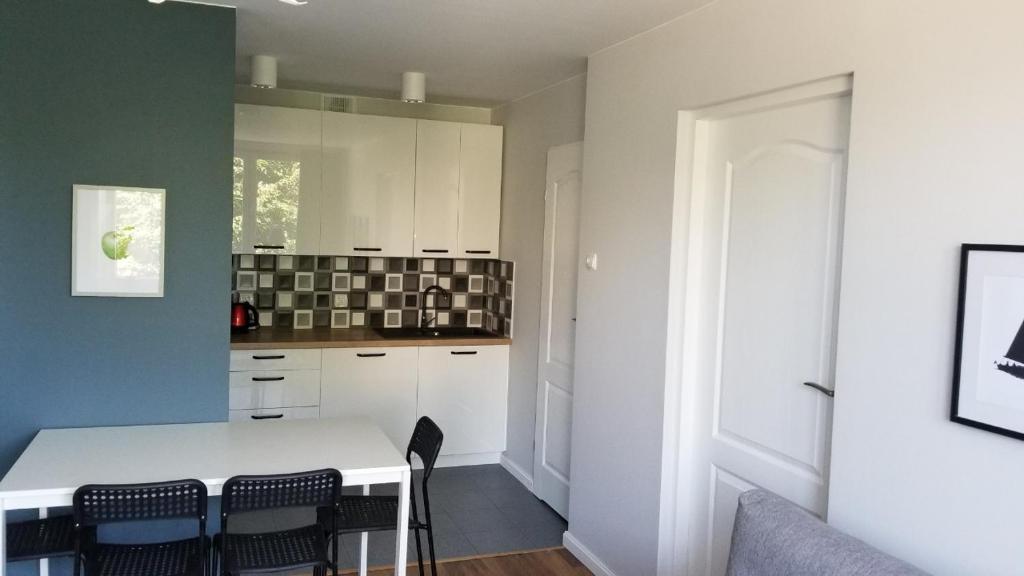 a kitchen with a white table and chairs at Apartament Turkusowy Ruciane-Nida in Ruciane-Nida