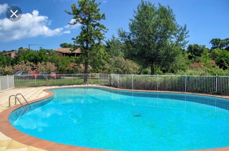 une grande piscine bleue avec une clôture dans l'établissement Marina di pinarello, appt climatisé à 400m de la plage, à Zonza