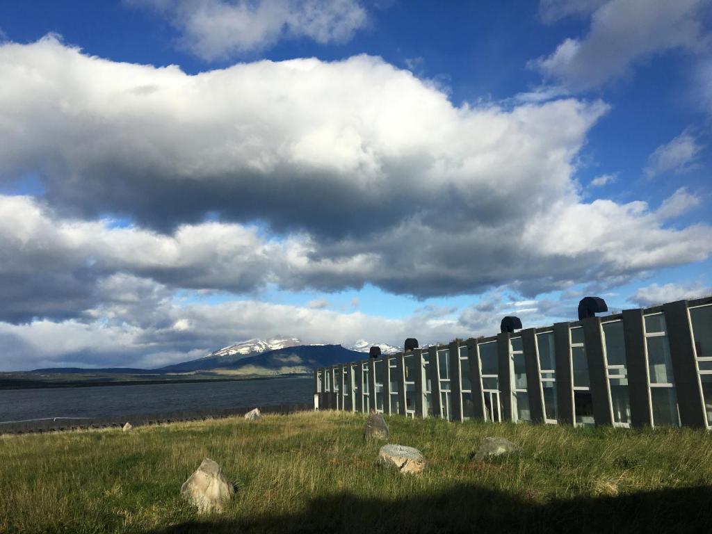 a fence in a field next to a body of water at Remota in Puerto Natales
