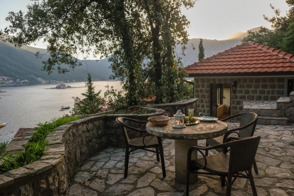 einen Tisch und Stühle auf einer Terrasse neben einem See in der Unterkunft Villa & Apartments Perasto in Perast