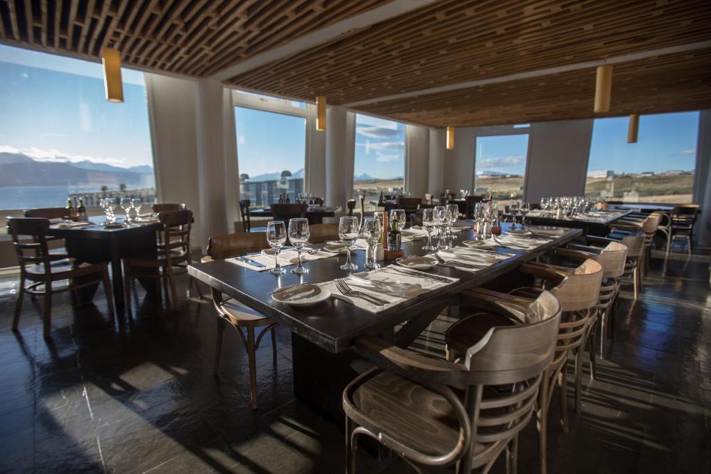 a dining room with tables and chairs and windows at Remota Patagonia Lodge in Puerto Natales