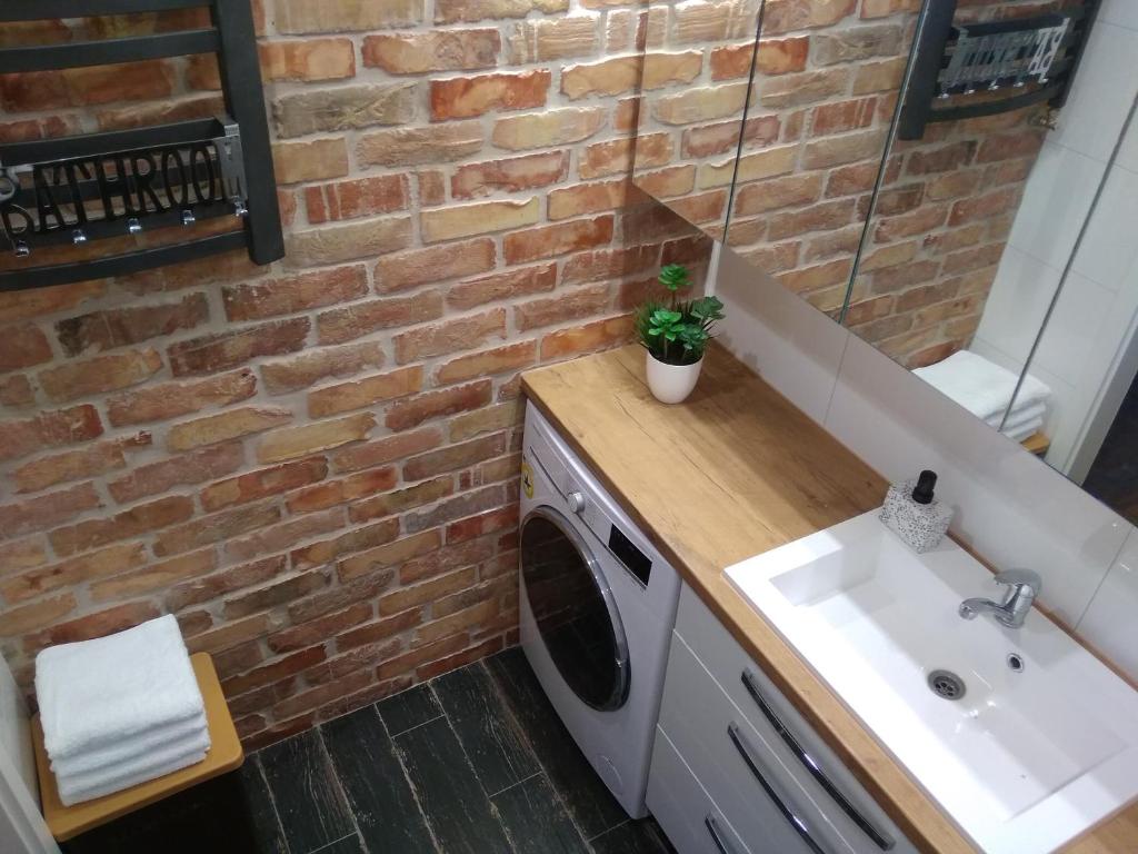 a washing machine in a bathroom with a brick wall at Kaktusik in Suwałki