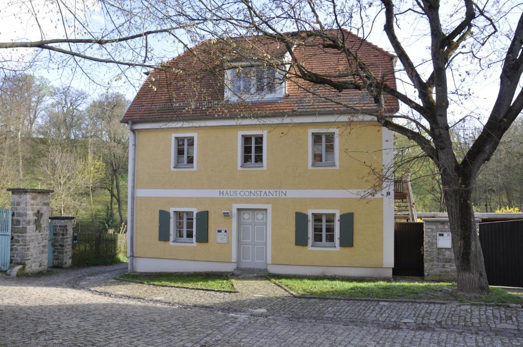 Una casa amarilla con un árbol delante. en Haus Constantin en Weimar