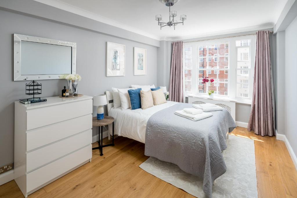 a white bedroom with a bed and a window at Homm - Hyde park 2 bedroom flat in London