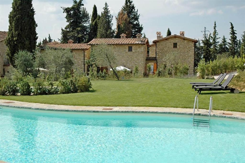 uma piscina com duas cadeiras e uma casa em Bellini em Gaiole in Chianti