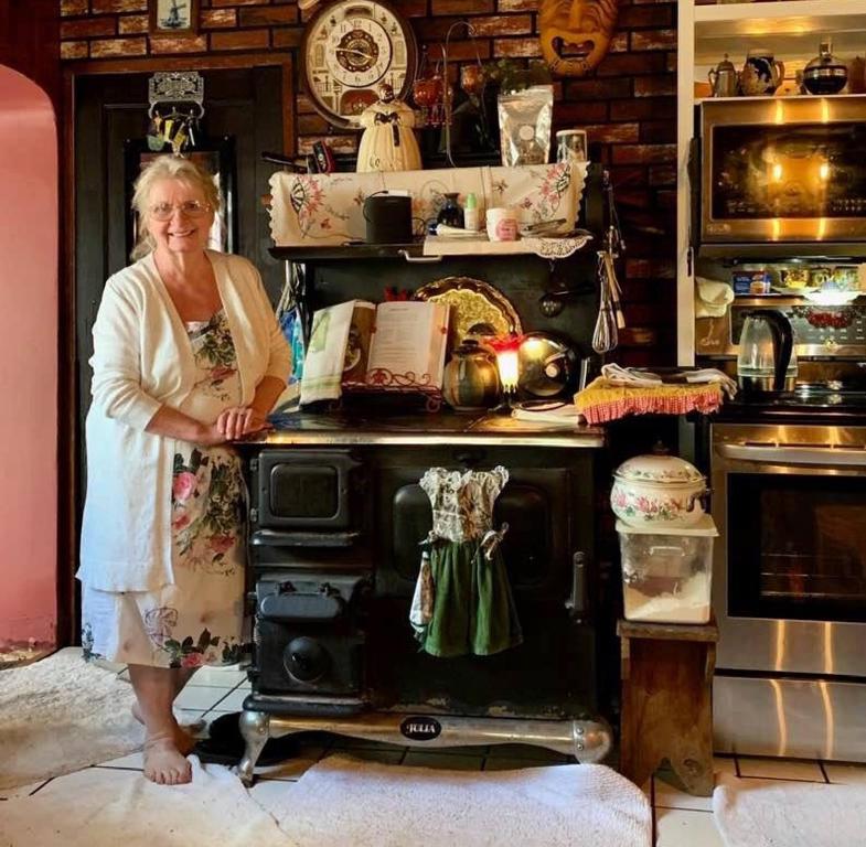 een vrouw die voor een oude oven staat bij Billie's Backpackers Hostel in Fairbanks
