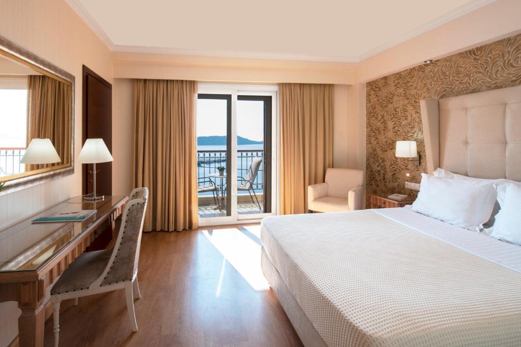a hotel room with a bed and a desk and a balcony at Karalis City Hotel in Pylos