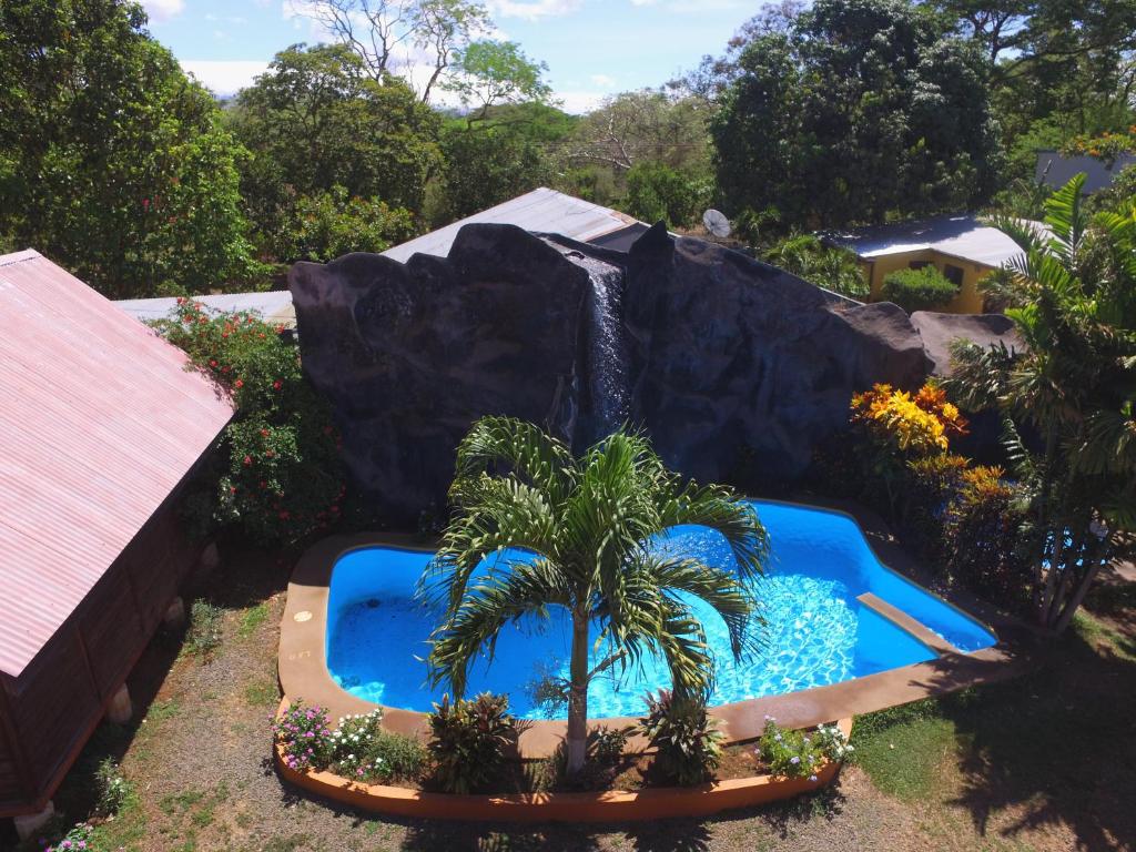 a water park with a fake waterfall and a palm tree at Hotel Cabanas La Teca in Liberia