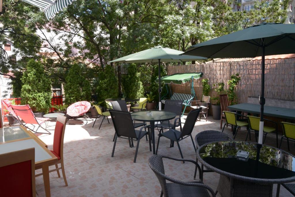un patio con tavoli, sedie e ombrelloni di Guest House GOLDEN COIN a Niš
