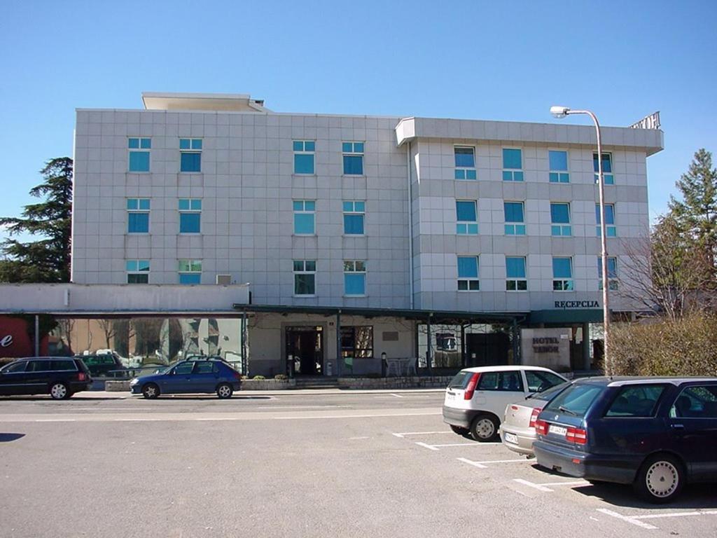 un grand bâtiment avec des voitures garées dans un parking dans l'établissement Hotel Tabor, à Sežana