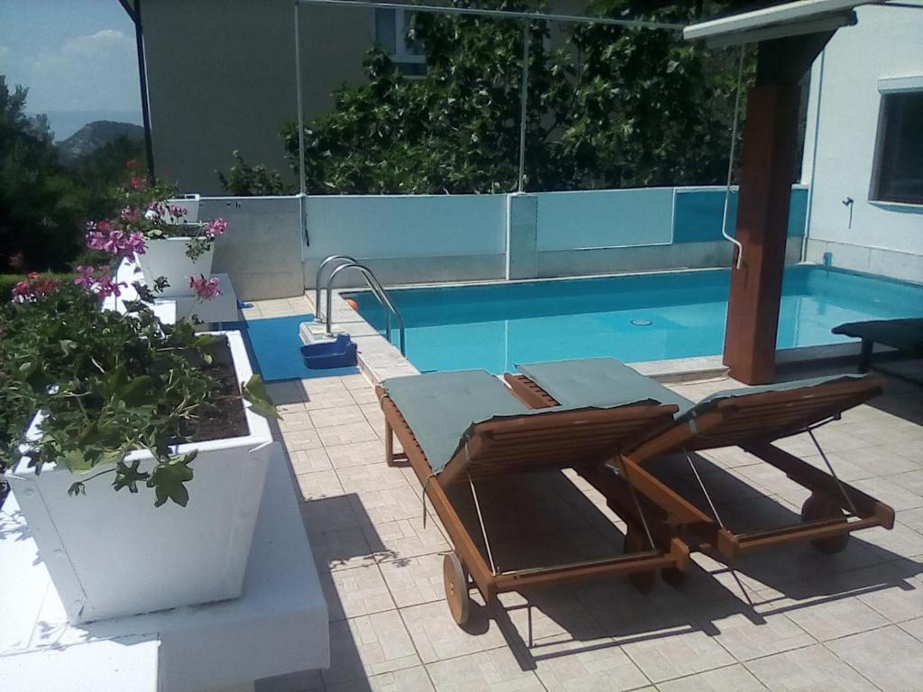 - une table et une chaise en bois à côté de la piscine dans l'établissement Vila Brig 108 - private swimming pool and jacuzzi, à Rijeka