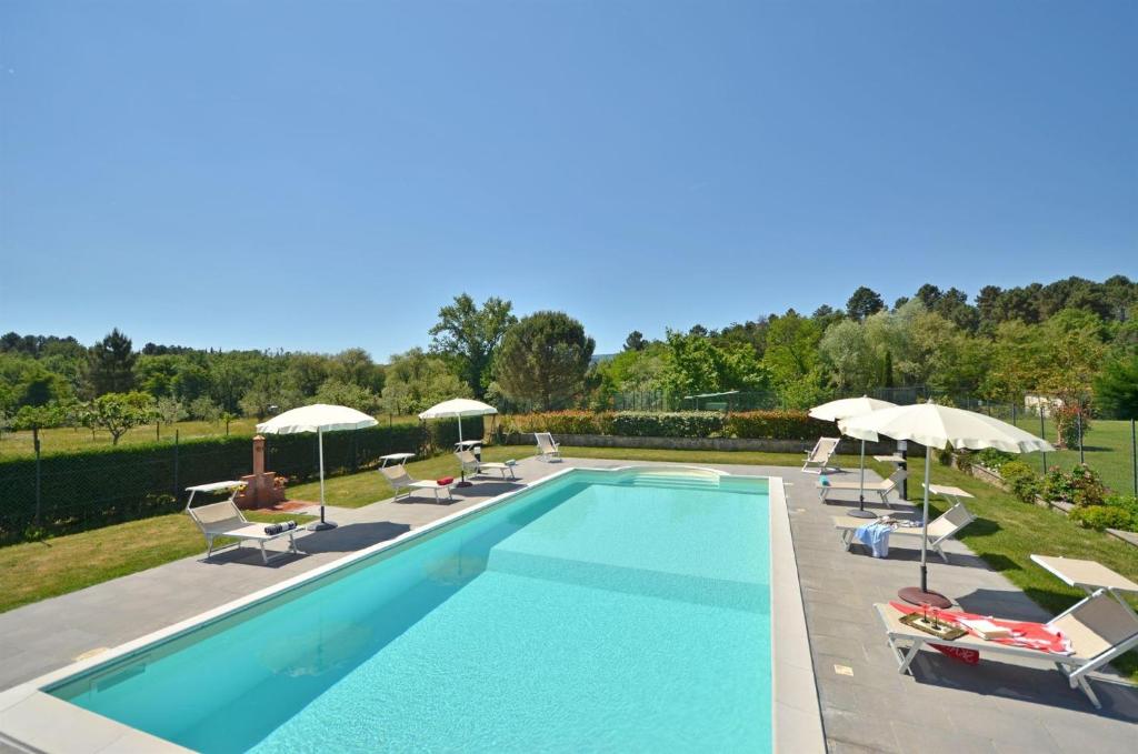 a swimming pool with chairs and umbrellas at Casa Il Pino in Cavriglia