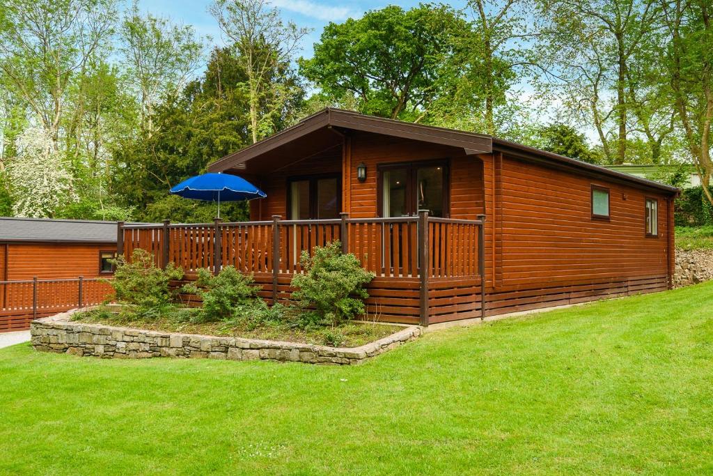 a wooden cabin with an umbrella in a yard at Woodlands Hotel & Pine Lodges in Grange Over Sands