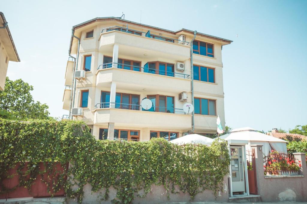 a tall white building with bushes in front of it at Dream House in Ahtopol