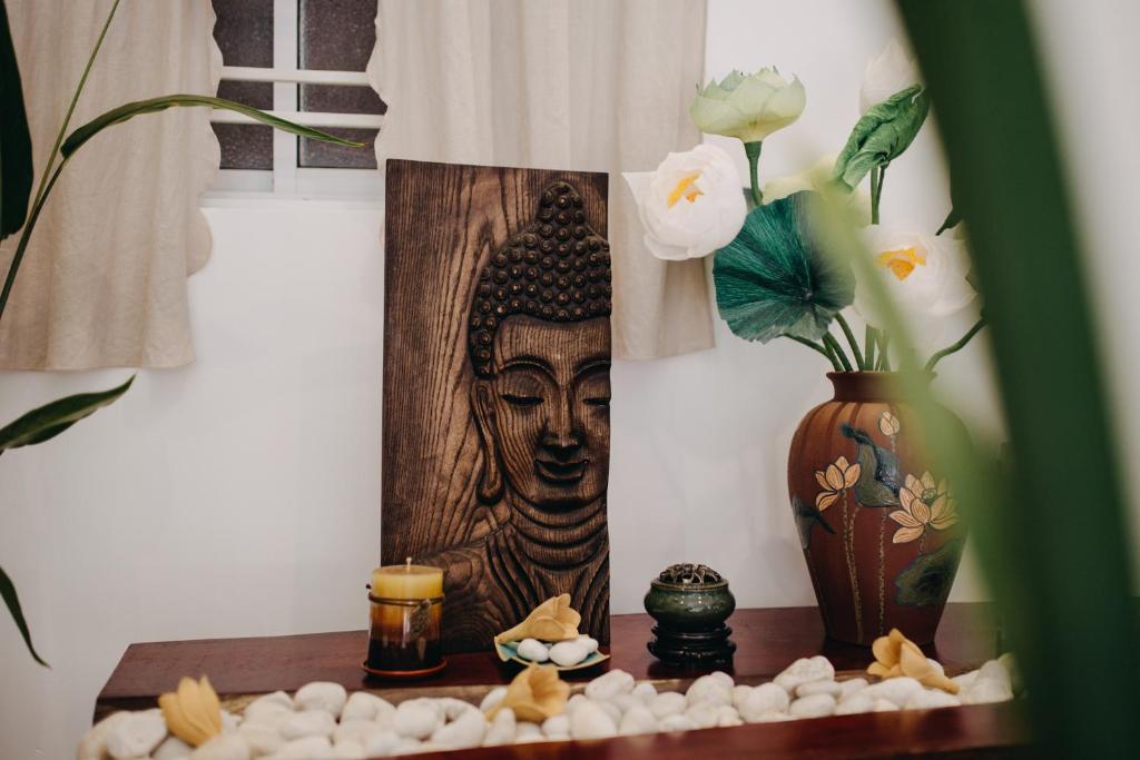 Tâm Homestay في هوى: طاولة مع تمثال و مزهرية مع الزهور