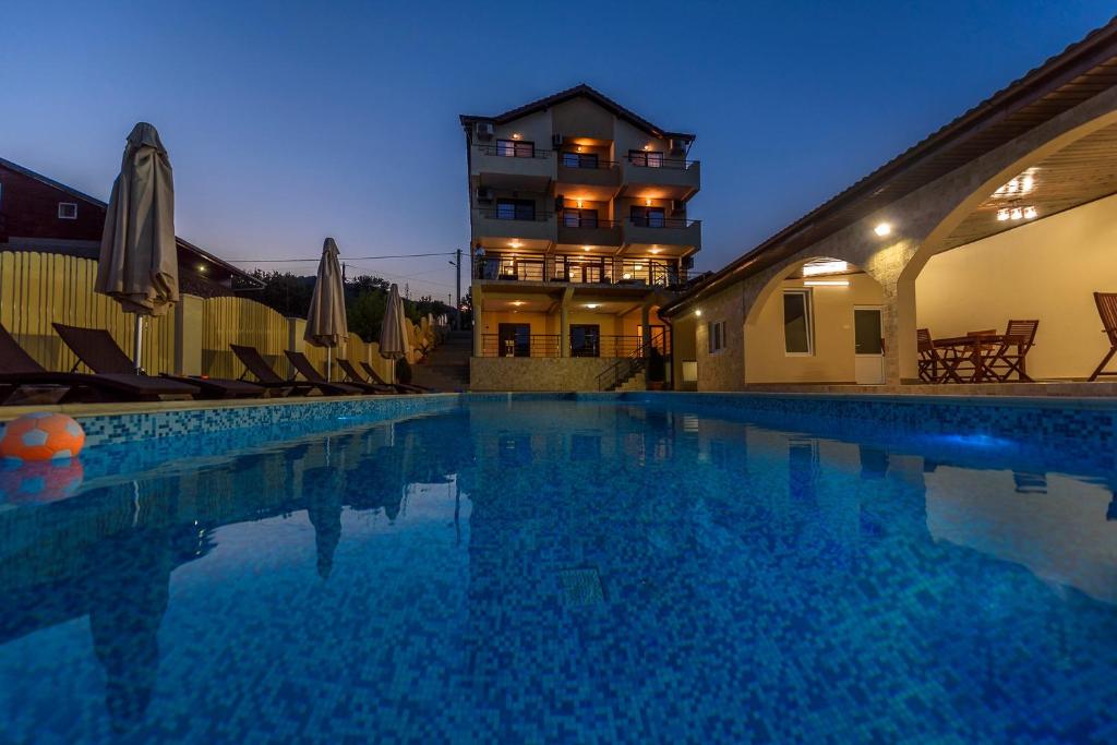 a large swimming pool in front of a building at Pensiunea Alex & Restaurant in Eşelniţa