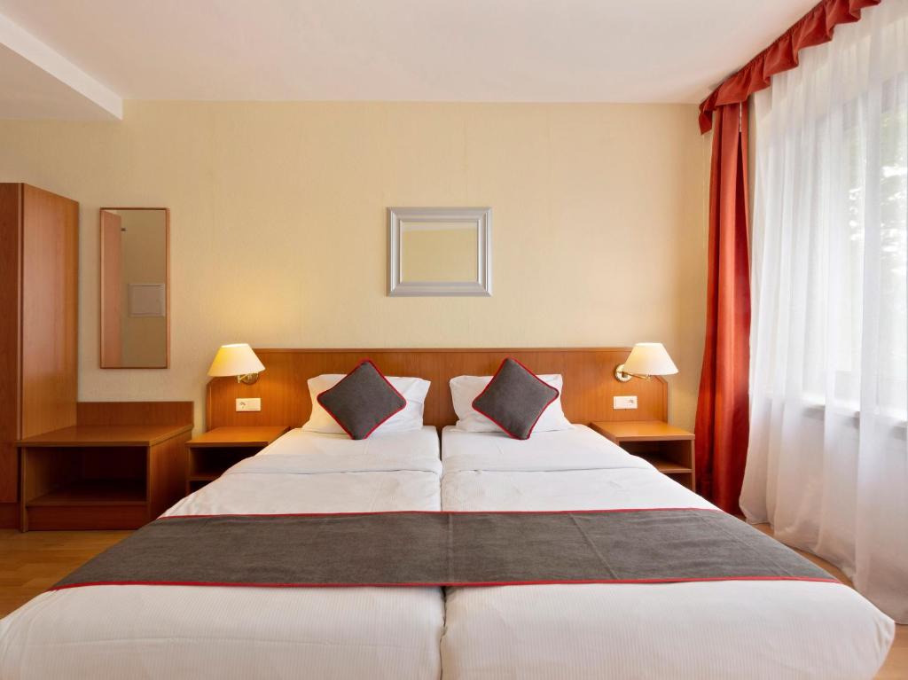 a hotel room with a large bed with two pillows at Hotel Bohemia in Berlin