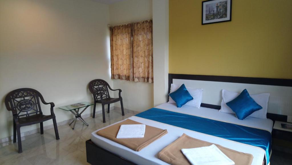 1 dormitorio con 1 cama con almohadas azules y 2 sillas en SEA WINDS en Ratnāgiri