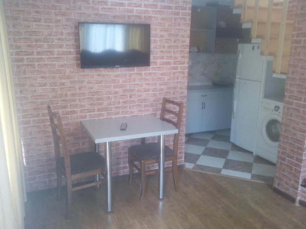 a kitchen with a table and chairs and a tv on a brick wall at malu in Kutaisi