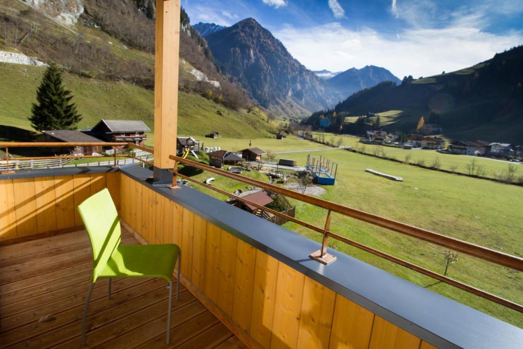 a green chair on a balcony with a view of mountains at Familienhotel Oberkarteis in Hüttschlag