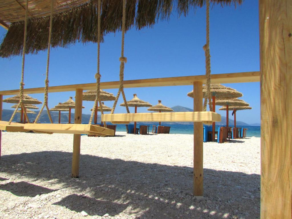 a swing on the beach with chairs and umbrellas at Blue Paradise Hotel in Orikum
