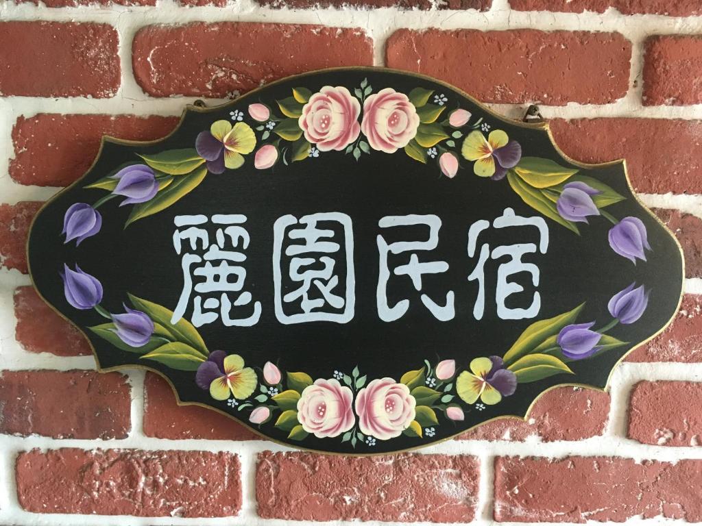 um sinal com flores numa parede de tijolos em Dong Gang Li Yuan Homestay em Donggang