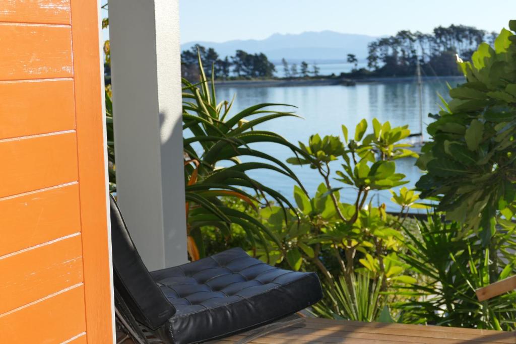a black chair sitting on a porch with a view of a lake at Waterfront Bliss in Nelson