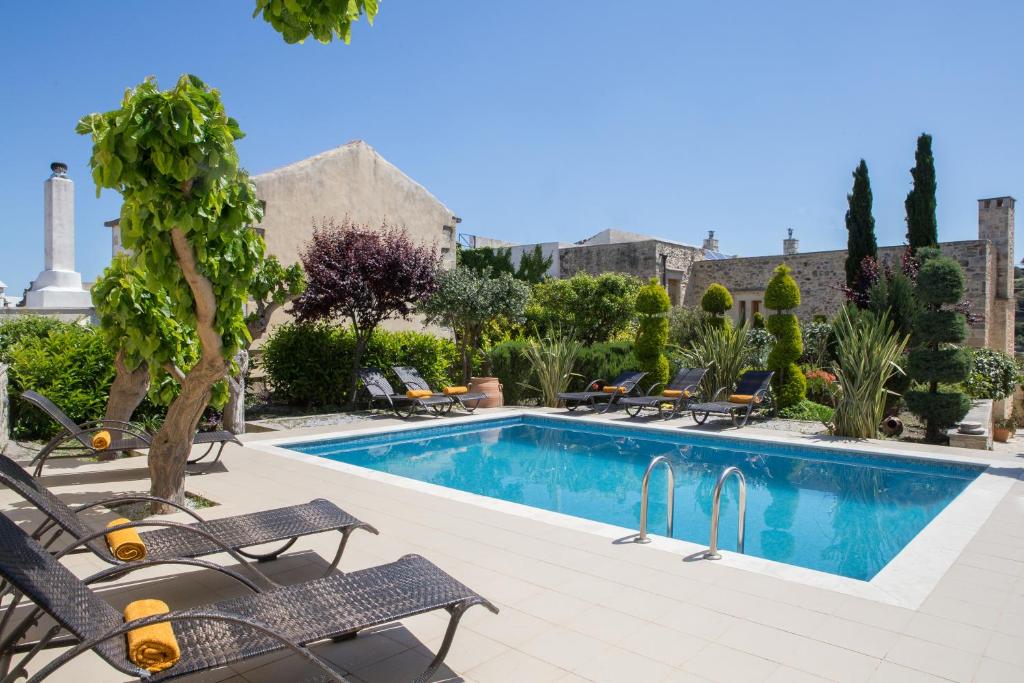 a swimming pool with chairs and a resort at Arcus Suites in Argyroupolis