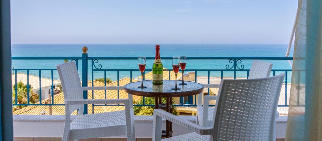 een tafel met 2 flessen en wijnglazen op een balkon bij Kaskanis Apartments in Vráchos