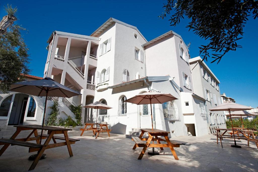 a building with tables and umbrellas in front of it at Résidence Aragon in Juan-les-Pins