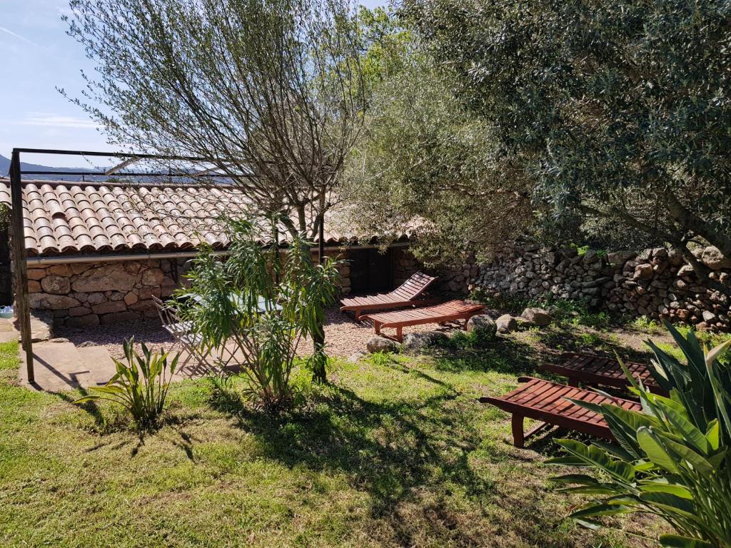 a garden with two benches and a building at Caseddu Di Poggiale in Figari