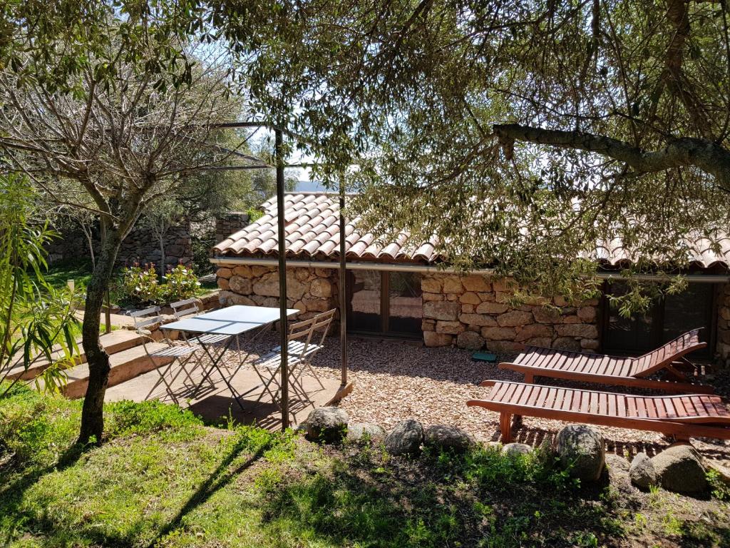a picnic table and two benches in a garden at Caseddu Di Poggiale in Figari