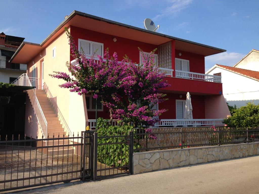 una casa rossa e bianca con una recinzione e fiori viola di Apartments Renko a Stari Grad (Cittavecchia)
