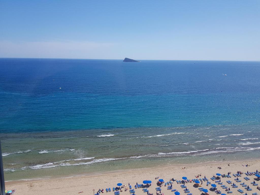 una playa con sillas y sombrillas y el océano en Torre Levante-Fincas Benidorm, en Benidorm