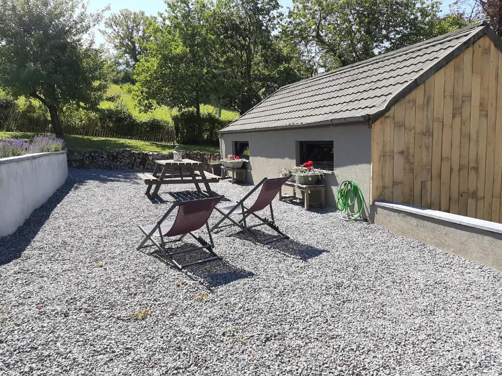 eine Terrasse mit 2 Stühlen, einem Tisch und einem Gebäude in der Unterkunft L'atelier in Durbuy