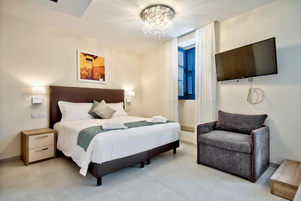 a bedroom with a bed and a chair at The Suites – Piazza Kirkop in Kirkop
