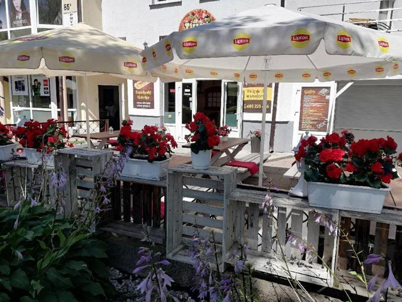 ウストカにあるUstecka Przystanの花と傘を飾ったテーブルのあるレストラン