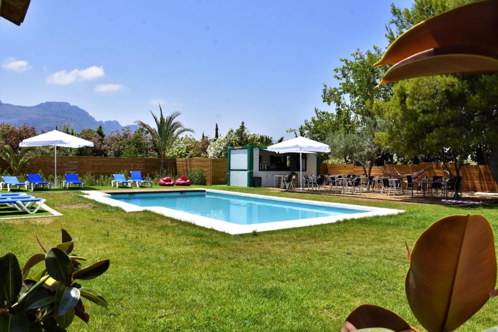 a swimming pool in a yard with chairs and umbrellas at Aqua House in Denia
